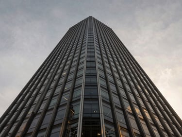 Low-angle wide shot of a modern glass and steel skyscraper under a crisp overcast sky, architectural symmetry