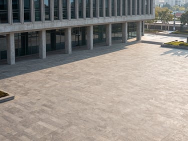 High-angle environmental photograph of a monumental civic plaza, crisp morning light, sharp structural lines of concrete and glass, minimal composition with generous negative space.
