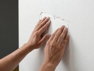 Close-up of a professional painter's hands carefully smoothing plaster on a wall, soft natural side lighting, sharp focus.