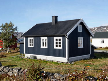 En velholdt enebolig i Vadsø omgitt av en ren, nymalt treterrasse og grønn hage under det klare, kjølige arktiske dagslyset, 35mm
