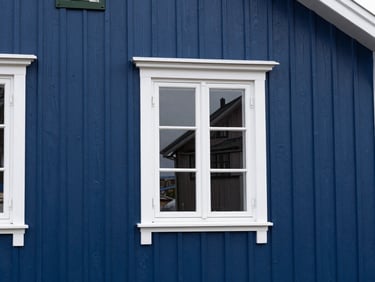 A freshly painted deep blue wooden house wall in Vadsø, clean white trim, immaculate finish under crisp daylight
