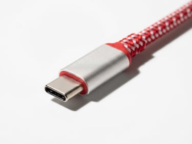 Macro close-up of a red-and-white braided USB-C connector on a stark white background with sharp shadows