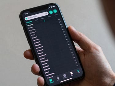 Android phone held at working angle displaying a utility app with structured data tables, monospace typography, dark UI, status indicators in teal, neutral daylight lighting