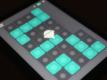 Close-up of an Android game UI screen showing a grid-based puzzle mechanic, touch targets highlighted in teal, frame counter visible in corner, dark background, even studio lighting