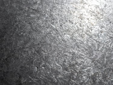 Macro shot of a textured steel sheet surface showing fine microscopic roughness pattern, high-contrast side lighting