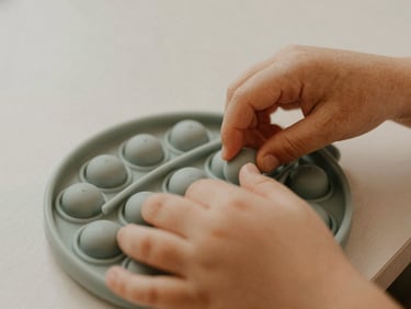 Close-up of a child's hands interacting with textured sensory tools, soft diffused daylight, muted earth tones, intimate eye-level perspective.