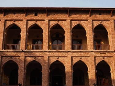 Grand hotel lobby facade with high ceilings and traditional brick archways on Mall Road Lahore, soft golden-hour light, editorial 35mm