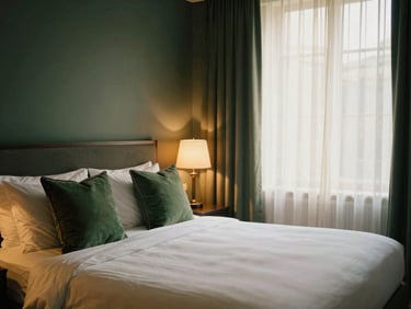 A beautifully styled hotel guest room with crisp white linen, deep green cushions, warm ambient bedside lamps, soft sunlight filtering through sheer curtains, 35mm