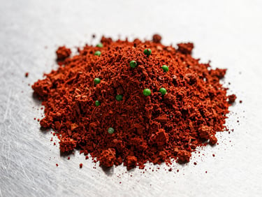 Macro shot of finely milled red spice powder on a stainless steel surface, crisp industrial lighting.