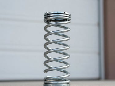 Close-up of a new, heavy-duty steel torsion spring, clean and robust, with a blurred background of garage door components, sharp focus