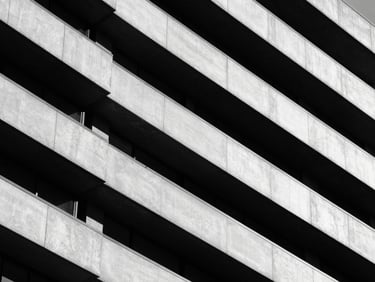 Architectural close-up of a modern corporate building facade, sharp diagonal shadows, high-contrast monochrome, minimalist