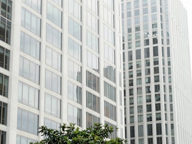 Minimalist architectural close-up of modern high-rise buildings in Sydney CBD, bright natural daylight, clean glass reflections, subtle green foliage at the bottom