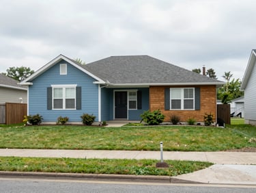 A modest suburban house with a green lawn under soft overcast daylight, real estate transaction completed, authentic local streetscape
