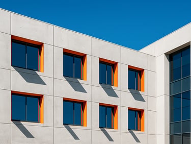 Bright architectural photography of a modern concrete office facade in Doral, high-key natural daylight, sharp geometric shadows, vivid blue sky, 35mm.
