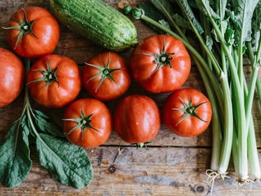 Overhead flat-lay of freshly harvested heirloom produce from a local farm, vibrant colors, natural textures, soft north-facing daylight, rustic wooden background.