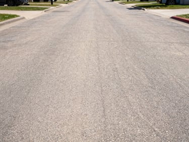 Sharp focus shot of a spotless asphalt commercial driveway completely cleared, bright direct Texas sunlight.