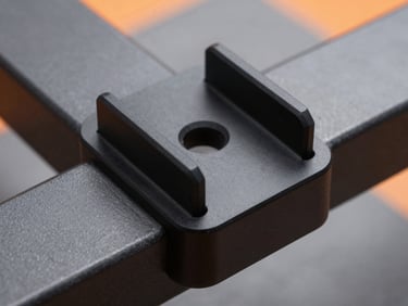 Macro shot of a finished custom black polymer bracket mounted securely onto an industrial metal frame, showing perfect fit and clean matte finish