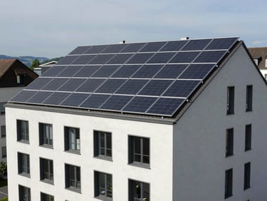 Contemporary multi-family residential building in Switzerland with sleek solar panels integrated into the facade and roof, crisp daylight.