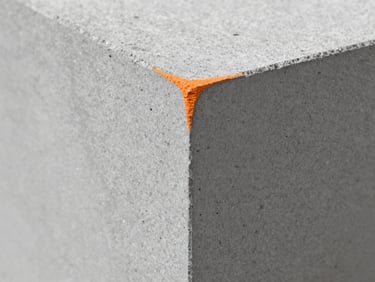 Macro close-up of a solid concrete block showing dense aggregate texture and clean sharp edges, industrial studio lighting, 35mm