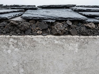 Macro shot of a core soil sample showing dense bedrock layers, high-contrast overcast daylight, cool concrete and slate tones, sharp focus, 35mm lens