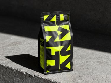 Hiperrealistic mockup of a coffee bag with bold geometric typography, placed on a concrete ledge, sharp shadows, neon yellow accents.
