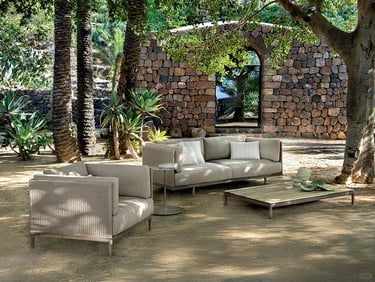 Garden seating with outdoor performance fabric, synthetic wicker, stone surfaces and natural materia