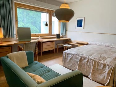 Warm bedroom and sitting area with wooden furniture, large window and natural light