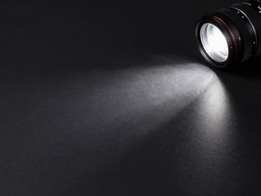 Wide shot of a high-contrast product scene — dark polished surface, single hard spotlight raking across an object from upper right, deep blacks, intense commercial precision — 2.39:1 cinematic frame, no people, graphic and bold