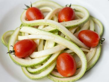 Overhead shot of a light zucchini noodle dish with cherry tomatoes, prepared at home, bright morning light