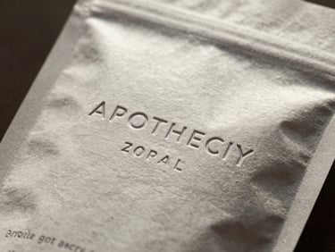 A close-up of custom debossed retail packaging for a boutique apothecary, showing tactile paper grain under directional window light.
