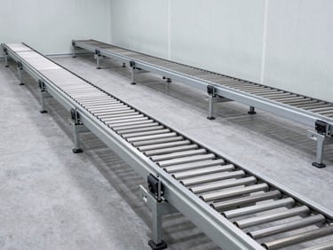 Wide-angle cleanroom view of an empty automotive testing chamber with steel conveyor tracks embedded in a gray concrete floor, crisp daylight