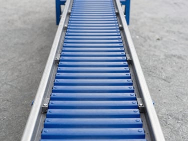 Straight-on close-up of a blue modular plastic conveyor belt designed for heavy vehicle transit, clean industrial daylight, slate gray background