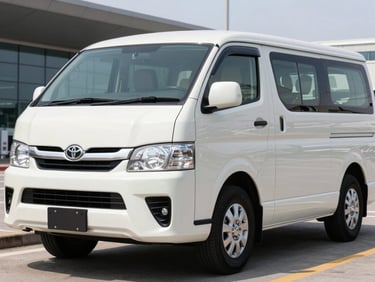 A clean white Toyota Hiace Premio parked near an airport terminal, low angle, bright professional automotive photography.