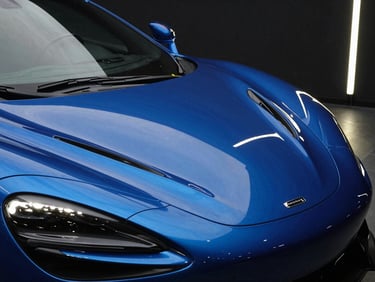 Dramatic automotive photography of a luxury sports car under linear LED studio lighting, sharp reflections on deep metallic blue hood, 35mm, high-contrast