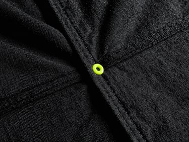 Macro product detail of heavy black loopback terry fabric, showing precise double-needle stitching and dense knit texture, dramatic key light with deep shadows.