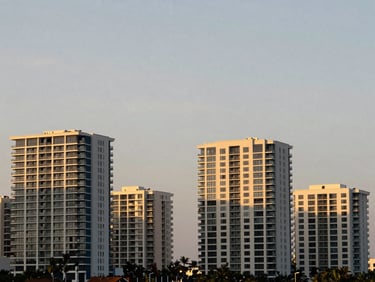 Quiet coastal Florida skyline at dusk, architectural details of modern buildings, soft golden hour light, muted navy and champagne gold tones, sharp focus, 35mm lens
