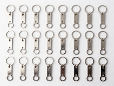 Overhead flat-lay of precision-machined metal keychains, arranged in a perfect grid, bright studio lighting, sharp focus.