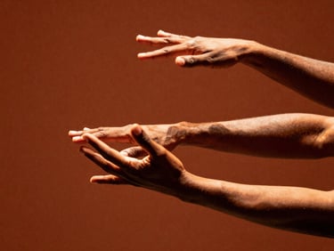 Close-up of expressive hands of an Afro-Brazilian dancer, warm theatrical spotlight, rich earthy terracotta background, high-contrast shadows