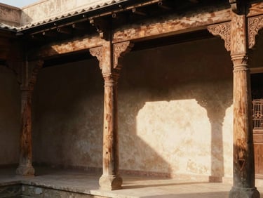 Architectural detail of a restored courtyard guesthouse with carved wooden pillars, warm morning light, soft shadows