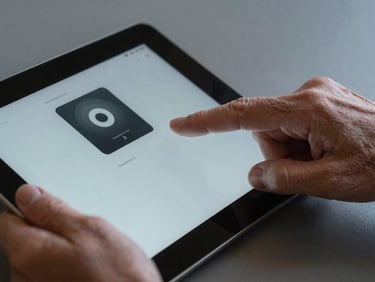 Tight macro crop of an older hand and a younger hand interacting with a tablet screen together, displaying a highly legible, accessible user interface. Cool studio lighting, sharp focus on the glass surface.