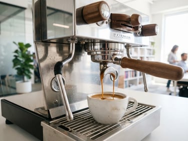 Close-up of a high-end commercial espresso machine, steam wand polished steel, rich crema pouring into a ceramic cup, bright clean office background, 35mm