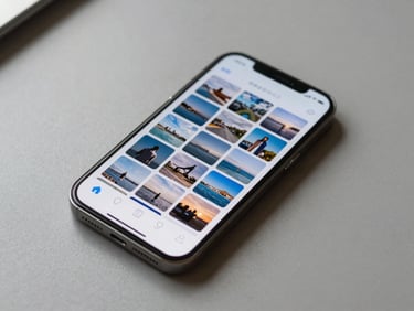 Top-down view of a smartphone resting on a table showing a neatly organized photo history grid interface with soft blue accents, clean daylight from the left, minimal and calm composition