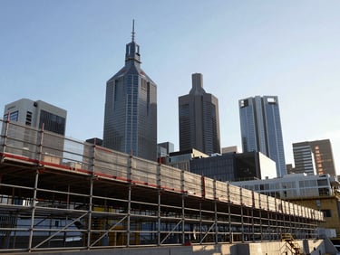 Low-angle architectural perspective of structural scaffolding lines against the crisp morning Melbourne skyline, clean geometric shadows.