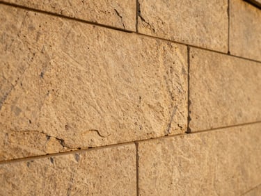 Close-up of hand-dressed limestone masonry on an elegant retaining wall, warm golden-hour light highlighting the rich texture, shallow depth of field.