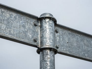 Close-up of a galvanized steel street sign post cross-section with bolt hardware visible, cool overcast industrial light, sharp metal detail