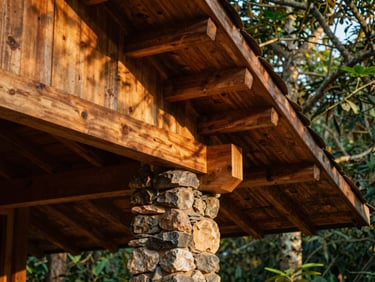 Close-up detail of timber rafters and local stone masonry in a forest lodge in Karnataka, warm wood grains, shadows casting patterns, medium format film.