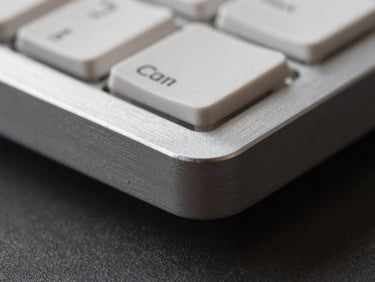 Macro close-up of a silver aluminum keyboard chassis corner, harsh lighting.