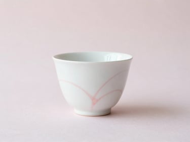 Small, centered product shot of a minimalist white ceramic pot with delicate pale pink hand-painted details, soft natural light, minimalist composition.