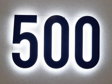 High-density Polifan letters with matte paint finish mounted on a textured office wall, sharp architectural photography, 50mm lens