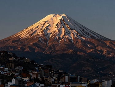 High-contrast portrait of the Illimani mountain towering over the city of La Paz, dramatic golden hour light hitting the snow-capped peak.